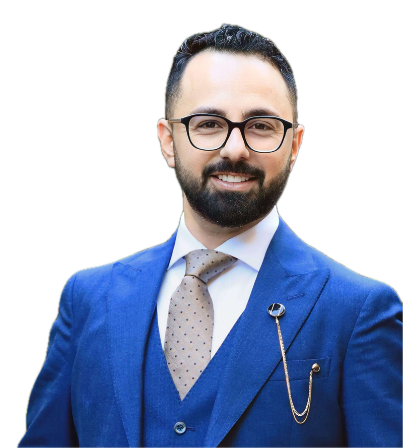 Khaled Sameer, smiling, in glasses, a blue three-piece suit and a polka-dot tie.
